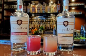 Bottles of Striped Lion Distilling rum next to two cocktails