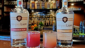 Bottles of Striped Lion Distilling rum next to two cocktails