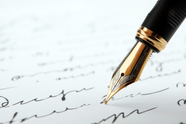 Quill pen poised upon page of close-up handwriting
