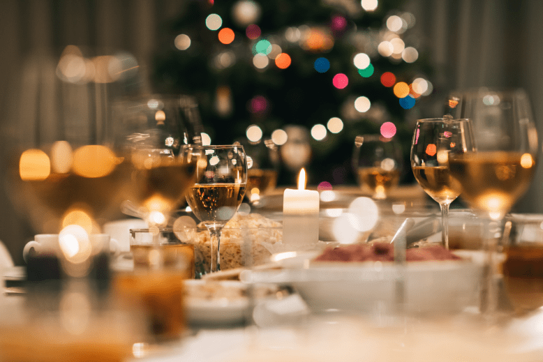 Christmas dinner table with wine glasses, candles and Christmas lights