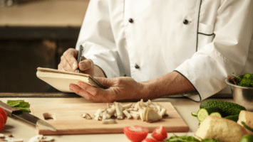 Chef writing in notebook in kitchen