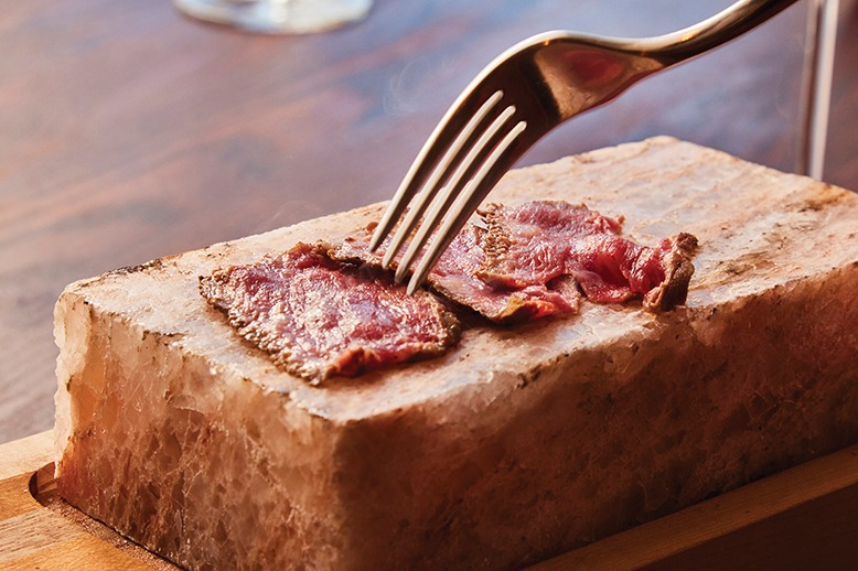 Thin slices of Wagyu strip steak on a 500-degree Himalayan-salt brick at Stage Left Steak in New Brunswick.