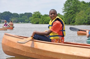A Camden student takes a break from paddling a wooden boat.