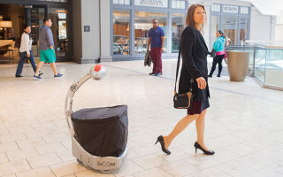 Five Elements Robotics CEO Wendy Roberts leads a loyal Budgee around Short Hills Mall.