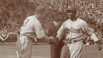 George "Shotgun" Shuba greets Jackie Robinson at the plate after Robinson smashed his first professional home run. Shuba, an Ohio native, would play alongside Robinson in three World Series with the Brooklyn Dodgers.