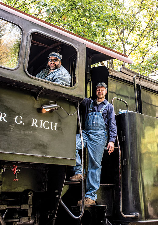 Engineer Don Chaudruc (in window) and student fireman Keegan Forke direct passengers on and off the train as it stops in Carpentersville, where passengers can stretch their legs at the pumpkin patch.
