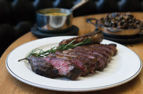 The expertly charred garlic-and-herb-rubbed bone-in sirloin, sliced, with a pan of wild mushroms on the side.