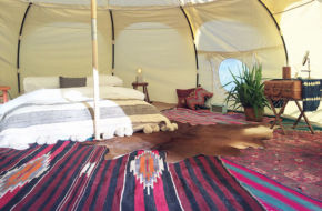 A fully furnished Lotus Belle tent from Wanderland Pop-Up includes queen bed with Peruvian blankets, Moroccan rugs, bedsides tables and soft lighting.