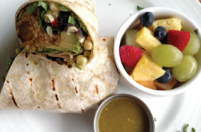 The vegan burrito , stuffed with plantains and served with avocado, black-bean-and-corn salsa, tomatillo sauce and a side of fruit salad.
