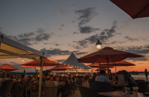 As daylight fades, patrons cozy up on the patio for the sun's extended bow.