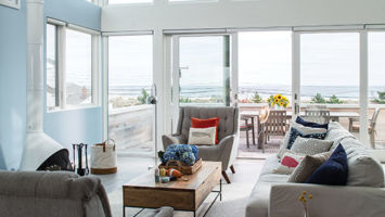 The main living area features a wall of windows looking out toward the beach.