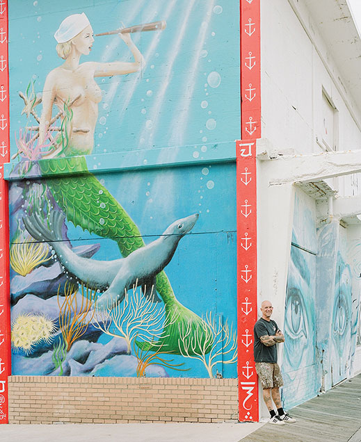 Porckhop stands next to his 20-foot mural "Ruthie &amp; Andre" that he painted for the Wooden Walls Project.