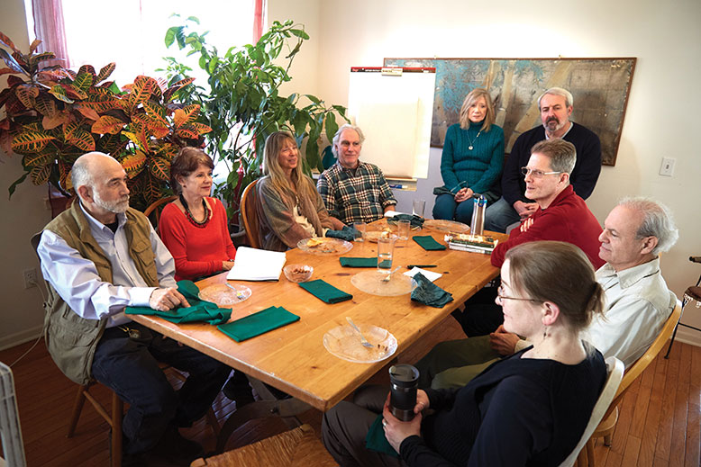 Would-be EcoVillage residents share proposals after a recent pot-luck dinner. From left: Jonathan Cloud, Victoria Zelin, Lois Schneider-Ross, Paul Schneider-Ross, Karyn Jorgensen, George Vallone, Larry White, Steve Welzer and an unidentified participant.