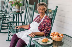 Cook Lucille Thompson, 89, takes a breather on the porch of the Chalfonte, where she has worked summers since girlhood. Beside her are her famous dinner rolls and crab cake.