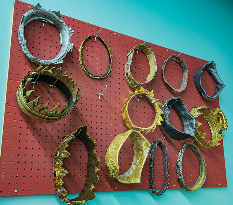 Crowns hang ingloriously on pegs in the costume shop.