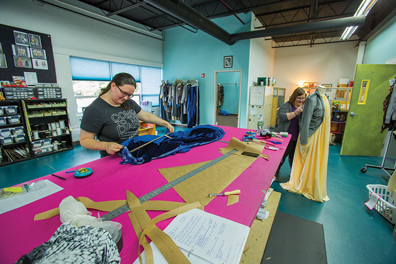 Jessica Adams, a costume-design and construction intern, measures fabric, while fellow intern Madison Borovatz mocks up a costume.