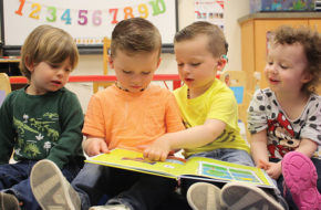 Children reading a picture book together in one of the three Sound Start Babies nursery rooms.