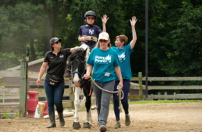 A child rides a horse with the help of employees at Pony Power Therapies