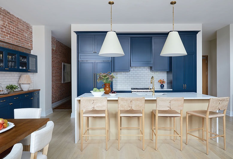 Kitchen in an apartment in Hoboken's Wonder Lofts has blue Shaker-style cabinets, brass hardware and a handmade-tile backsplash
