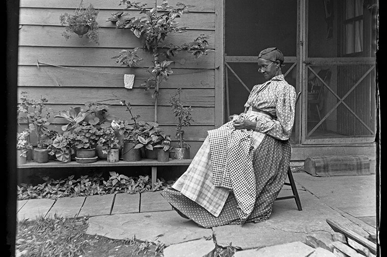 black and white photo of woman sitting on rocking chair on porch