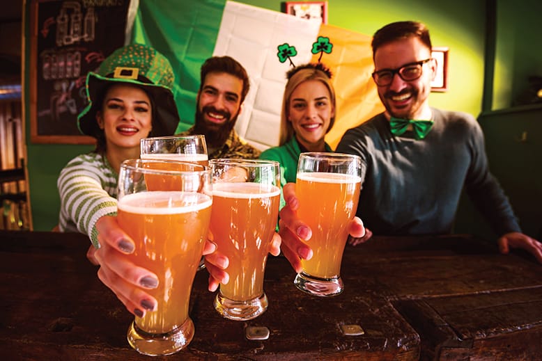 Group of friends holding beers and festively dressed for St. Patrick's Day
