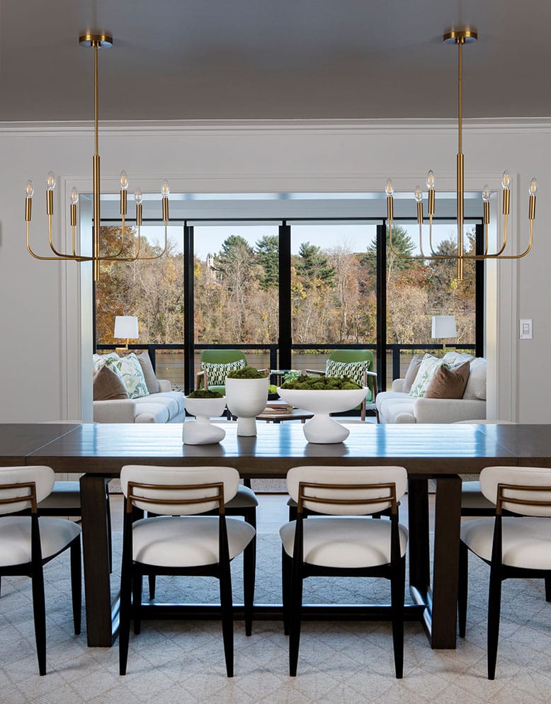 Dining table overlooks living room and large windows with a view of the outdoors