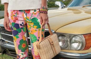 Woman in colorful floral pants in front of vintage yellow car