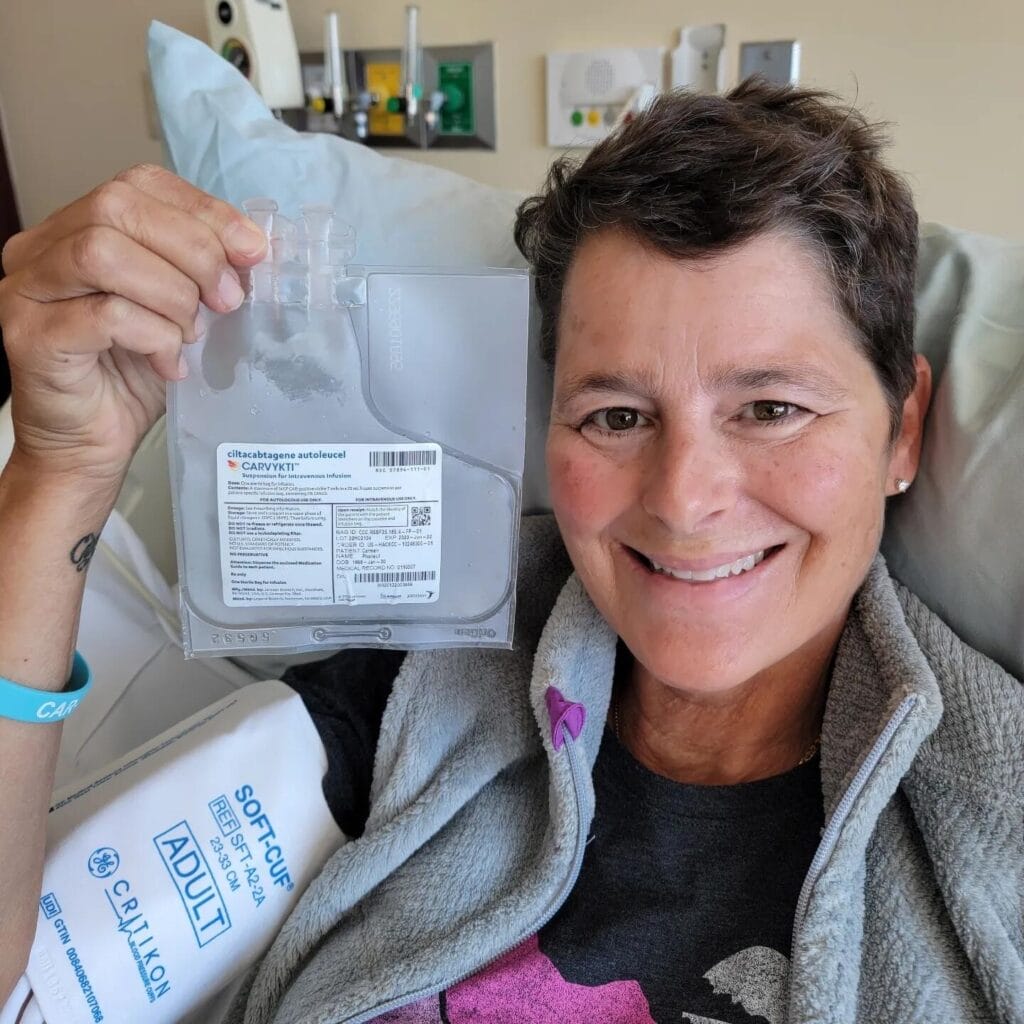 A smiling Carmen Phaneuf poses with packaging from the Carvykti treatment