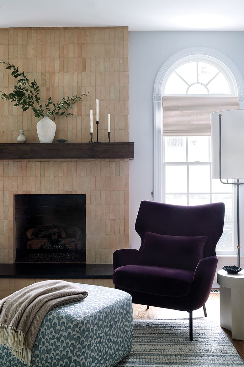A modern fireplace with an upholstered purple chair in the family room of a home in Somerset County, NJ