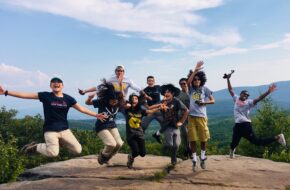 Students jump into the air at the top of a hike.