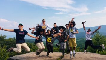 Students jump into the air at the top of a hike.