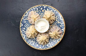 Georgian dumplings with sour cream on blue plate