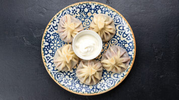 Georgian dumplings with sour cream on blue plate