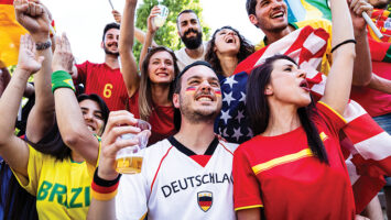 Soccer fans drinking and cheering at game
