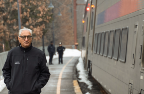 Kris Kolluri beside an NJ Transit train