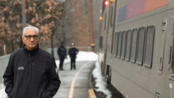 Kris Kolluri beside an NJ Transit train