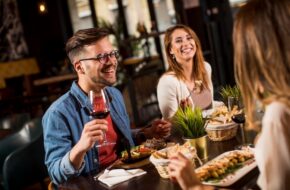 Group of happy young people having dinner in the restaurant