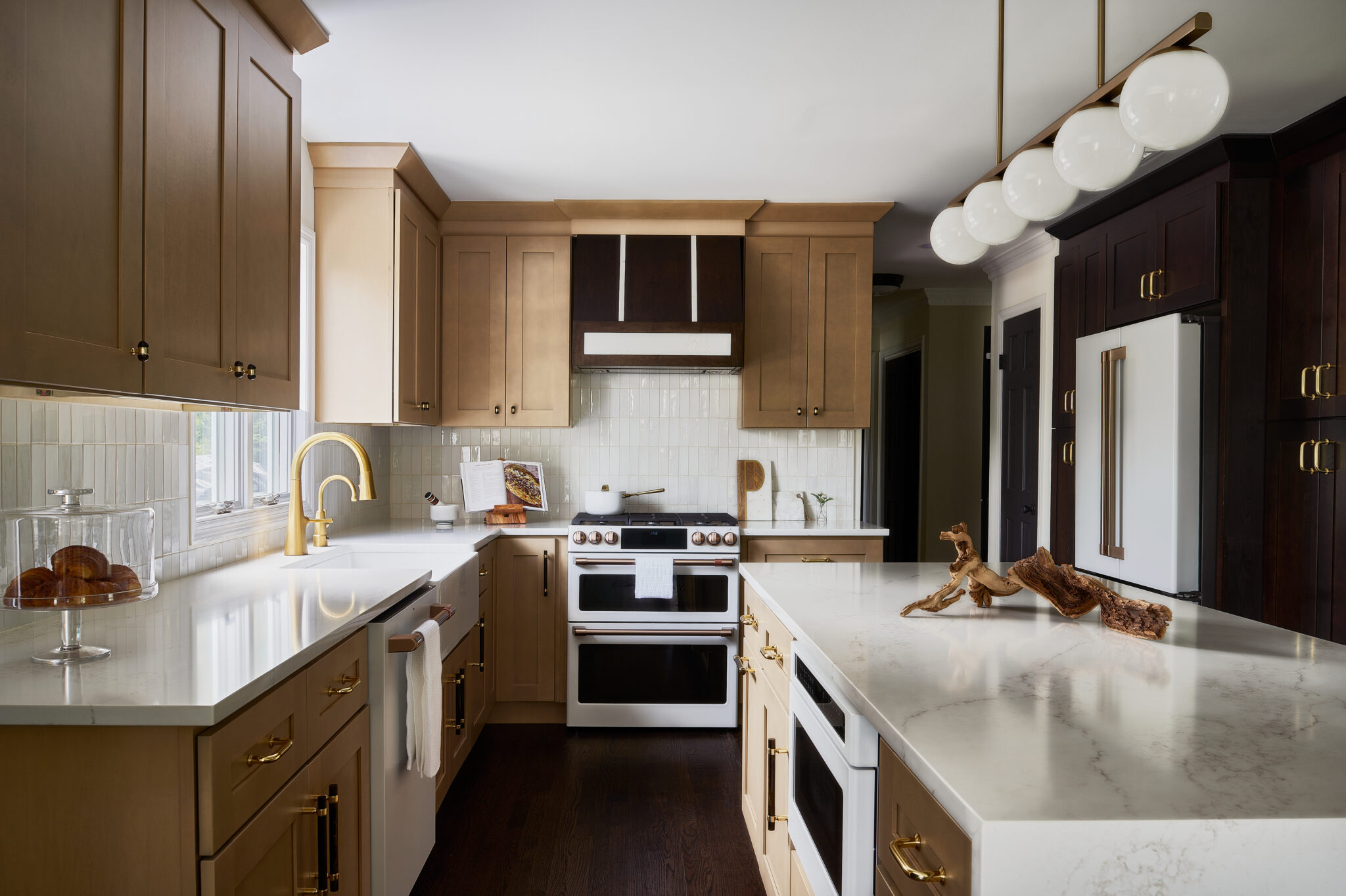 Inside a colonial home in Randolph, NJ, the redesigned kitchen balances dark and light, with espresso, warm oak, and white finishes. Alternating matte and glossy white subway tile on the backsplash bring textural dimension