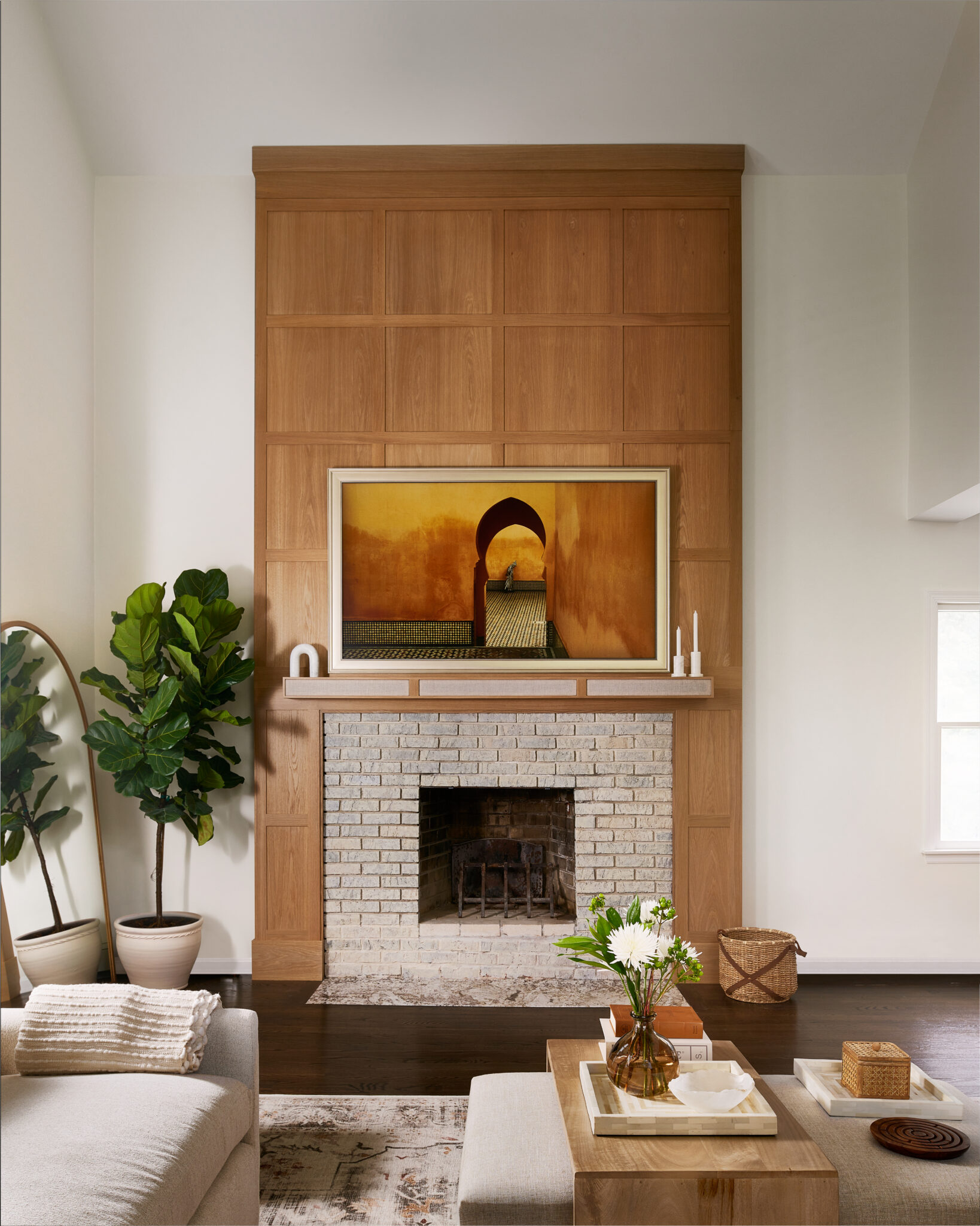Inside a colonial home in Randolph, NJ, solid white-oak panels around the fireplace add depth and warmth to the room, says designer Kathy Samaan. The hearth, once elevated, was lowered, its original brick retained. A custom mantel lined with acoustic fabric discreetly conceals a speaker and wiring. 