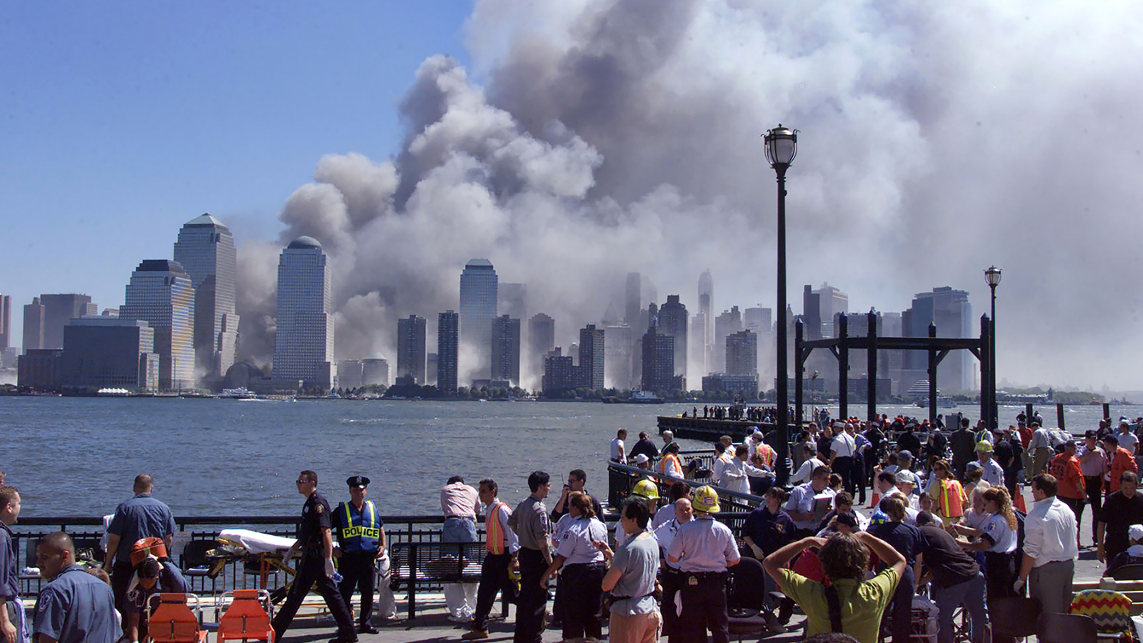 People gather on the waterfront at Exchange Place in Jersey City, just across the Hudson River from the World Trade Center, on September 11, 2001. 