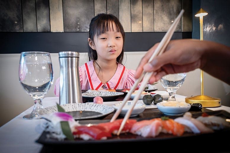 Young girl eyes sushi at a restaurant