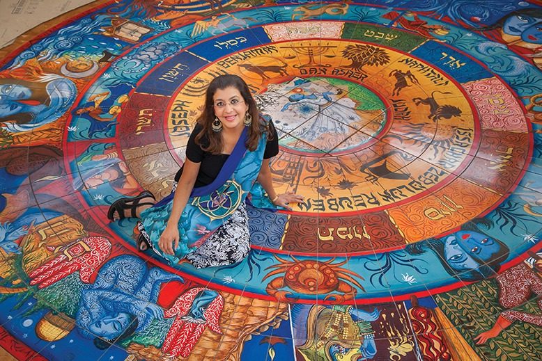 Artist Siona Benjamin sits on the tile mosaic she created.