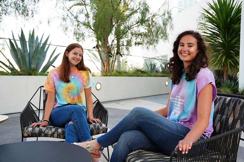 Lauren and Brooke Greenberg sit outside wearing tie-dye apparel from their brand, Tie Dye LAB