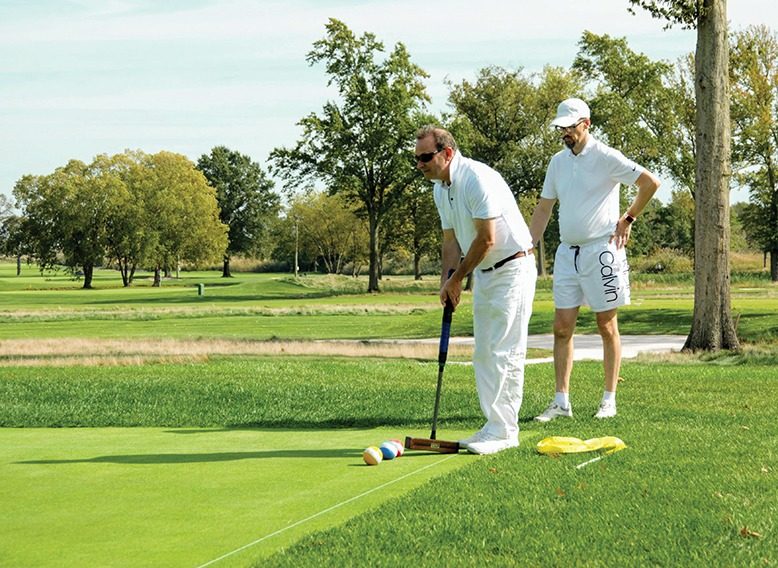 Two men playing golf croquet