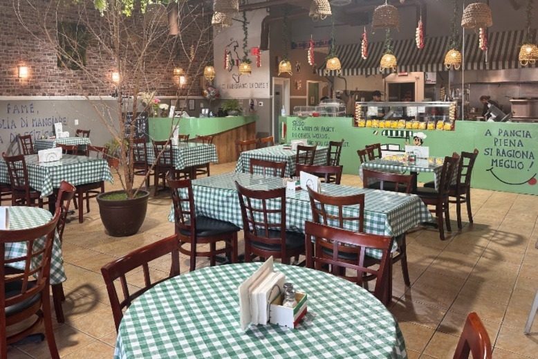 The inside of Lo Sfizio is full of round dining tables covered with green-checkered tablecloths