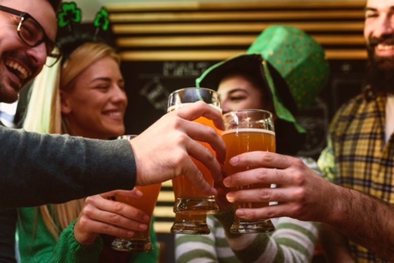 Friends dressed in St. Patrick's Day garb toasting beers