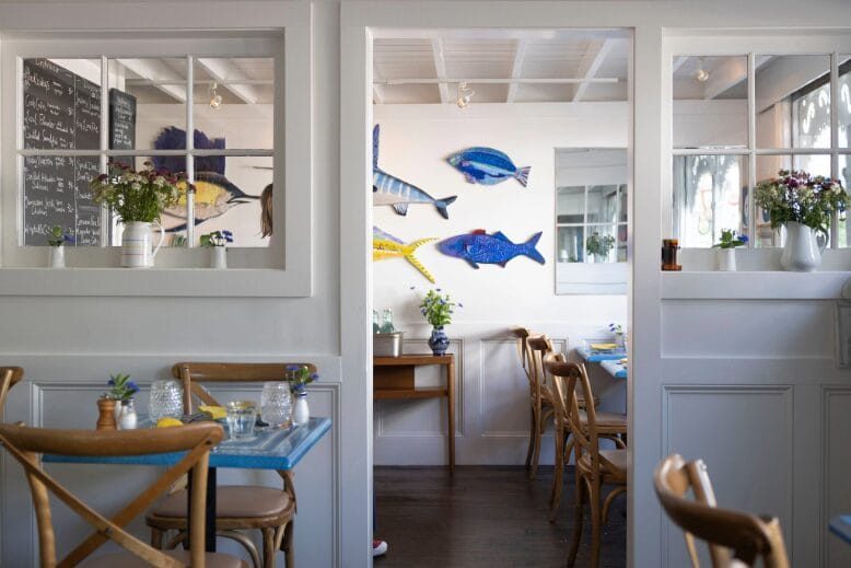 The white and neutral dining room at Louisa's Cafe in Cape May features charming pops of blue and yellow