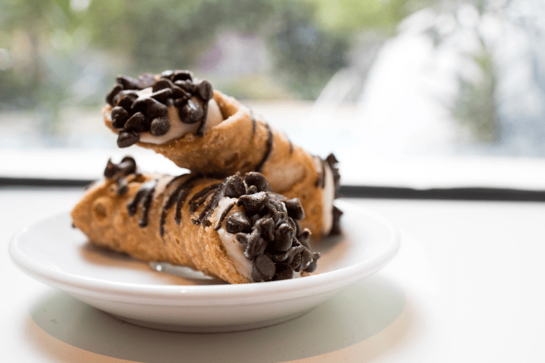 Two cannolis on a plate by a window