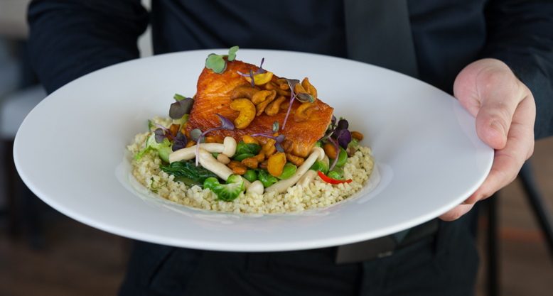 Seared Scottish salmon over spring vegetables, herbed bulgar and Asian broth, with tumeric-coated cashews.