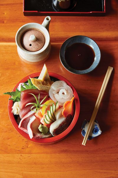 A bowl of chirashi—raw fish, vegetables, tamago (cold, sweet omelet) over rice.